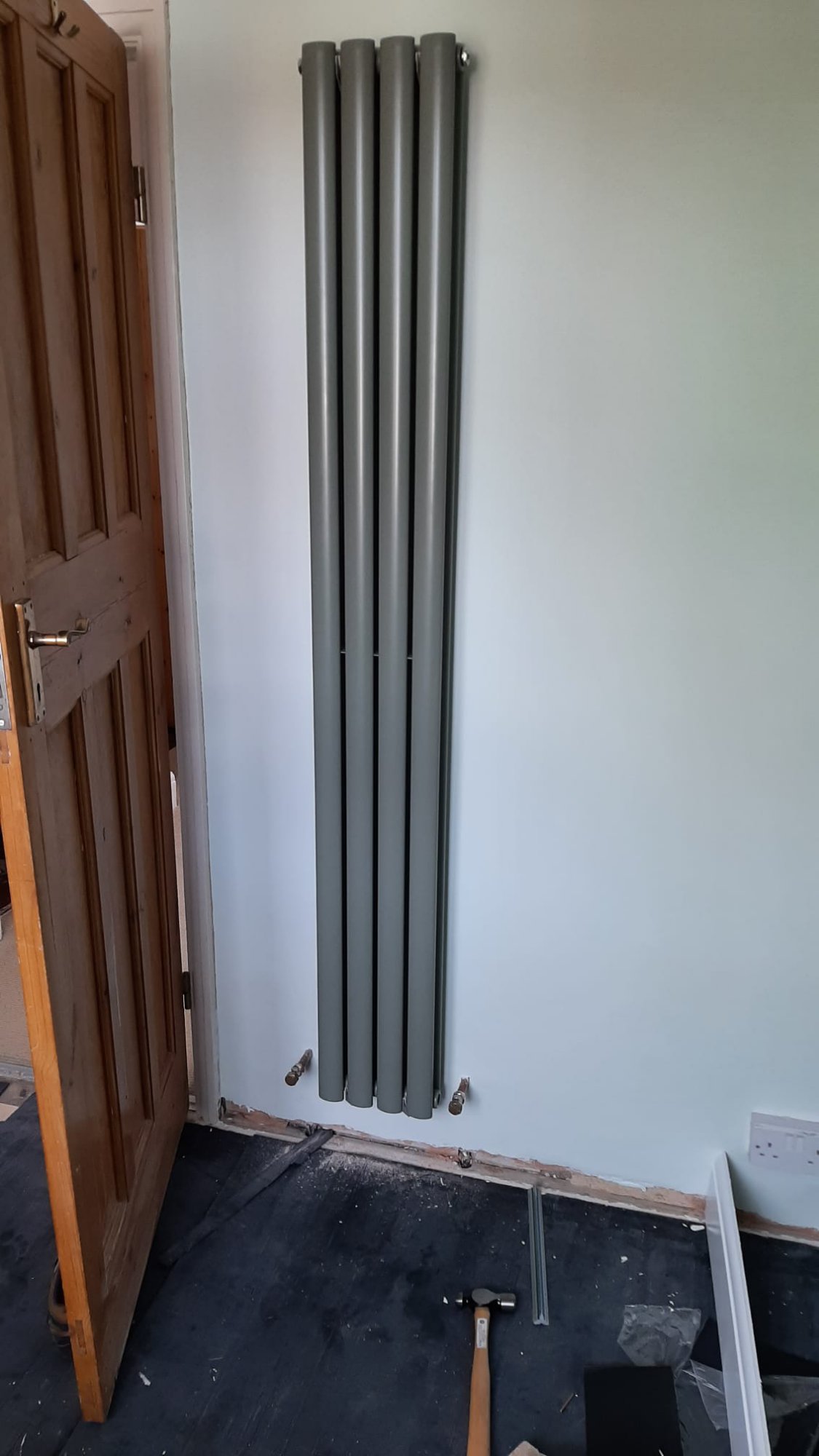 The new radiator, hung on the plastered and painted wall